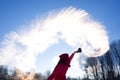 person pouring hot water up in the sky sunny winter day. Boiling water challenge which instantly freezes turns into snow if the