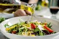 person pouring olive oil over a mediterranean salad Royalty Free Stock Photo