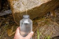 A person pours water into a bottle of mountain stream.