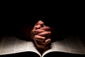 Person Praying with Hands on Top of the Bible