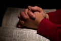 Person Praying with Hands on Top of the Bible