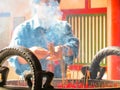 The person prays in the Buddhist temple and lights incense stick