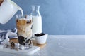 Person preparing bubble milk tea with tapioca balls at grey marble table against blue background. Space for text