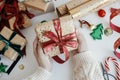 Person preparing modern gift box with red ribbon, golden wrapping paper, ornaments on white background. Merry Christmas! Hands Royalty Free Stock Photo