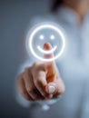 Person pressing a glowing smiley face icon representing positive feedback and customer satisfaction on a digital interface with a Royalty Free Stock Photo