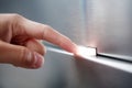 Person pressing illuminated button on textured metallic surface with soft focus background creating modern and minimalistic Royalty Free Stock Photo