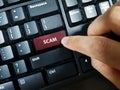 A person pressing the keyboard key with the word `SCAM`