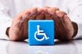 Person Protecting Cubic Block With Disabled Icon