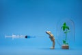 A person protects his immune system in the form of a green sprout in a flask from a vaccine with a syringe. Background.