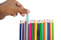 Person pulling a blue color pencil crayon from a row of different color pencils Royalty Free Stock Photo
