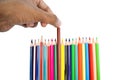 Person pulling a brown color pencil crayon from a row of different color pencils Royalty Free Stock Photo