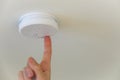 A person push the test button on a automatic smoke detector fire alarm in the ceiling. Royalty Free Stock Photo