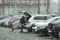 A person puts his shopping in the trunk of the parked car during a snowstorm in early spring.