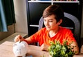 A person putting coin into piggy bank. Happy boy insert money coin in piggy bank, saving money concept. Royalty Free Stock Photo