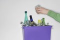 Person putting jar into recycling container filled with empty glass vessels