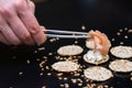 Person putting salmon with sticks on crackers with cream cheese