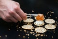 Person putting salmon with sticks on crackers with cream cheese