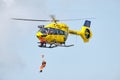 Person rappels down from a hovering ADAC rescue helicopter, in flight shot.