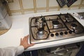 Photo of a person reaching for a pot on a stove