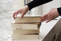 A person reading books near the window. Hands turns over book page