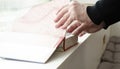 A person reading books near the window. Hands turns over book page Royalty Free Stock Photo