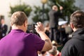 Person recording by zooming with the mobile a concert of a classical band of music abroad on a sunny day