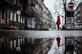 Person in a red coat walking in the city on a rainy day with reflections in a puddle