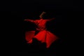 Person in a red dervish costume spinning on a black background Royalty Free Stock Photo