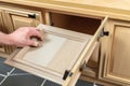 person, repairing broken kitchen cabinet door, with new replacement in hand