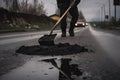 person, repairing pothole in the road surface with shovel