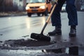 person, repairing pothole in the road surface with shovel