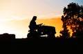 Person on a Ride On Lawn Mower on Farm at Sundown Royalty Free Stock Photo