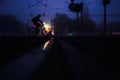 Person riding a bicycle across the street captured at night