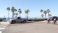 Person riding bicycle, palm trees and people in coastal pacific resort Oceanside, California USA