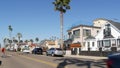 Person riding bicycle, palm trees and people in coastal pacific resort Oceanside, California USA.