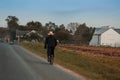 A person riding a bicycle on the pathway near farmhouses surrounded by green trees