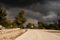 Person riding a bicycle on the road under the dark cloudy sky