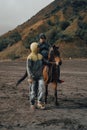 person riding a horse with his guide at bromo indonesia