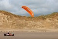 Person riding a kite buggy in a desert wearing a protective helmet