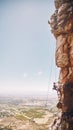 Person rock climbing on a mountain cliff for a challenge in nature with a blue sky and copy space. Woman climber on a