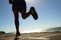 Person, running and asphalt at beach for fitness, workout or outdoor cardio training on a sunny day. Closeup of athlete