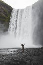 Person running to Skogafoss Iceland waterfall. Powerful stream, dramatic view