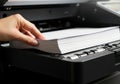 Hand places stack of white paper into a printer scanner tray Royalty Free Stock Photo