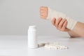 A person& x27;s hand with an elastic bandage and a jar of calcium or chondroitin tablets. Treatment of fractures, sprains