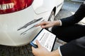 Person Examining Damaged Car While Filling Insurance Claim Form