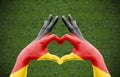 Person`s hand forming a heart with the flag of Germany - love towards football concept