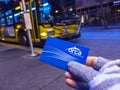 Person`s hand holding a bright blue transit pass card in front of a Bellevue Metro Transit Bus at the transit center downtown at