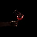 person s hand holding glass red wine splashing out glass. High quality photo Royalty Free Stock Photo