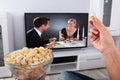 Person`s Hand Holding Popcorn While Movie Plays On Television Royalty Free Stock Photo