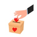 A person`s hand puts a heart in a donation box. the concept of kindness, generosity, love, donation